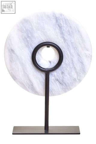 A sleek black metal stand holding a zoro small round round dia 20cm white marble disc sculpture with gray veining